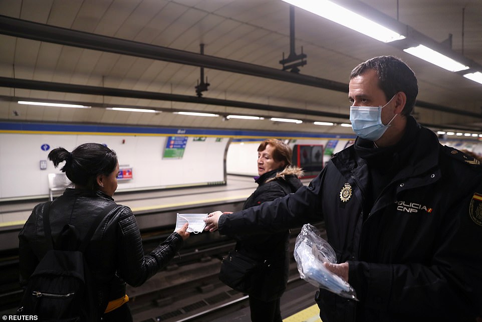 Một cảnh sát phát khẩu trang miễn phí cho người dân, cũng như tự đeo một chiếc cho mình tại một ga tàu điện ngầm Madrid, Tây Ban Nha vào ngày hôm nay (ảnh trái), và hành khách giữ khoảng cách an toàn khi đi tàu điện ngầm.