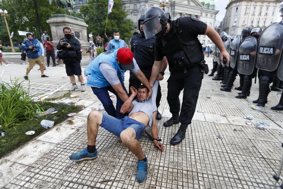 Cảnh sát tạm giữ một người hâm mộ bóng đá bên ngoài dinh tổng thống nơi Diego Maradona được an nghỉ.