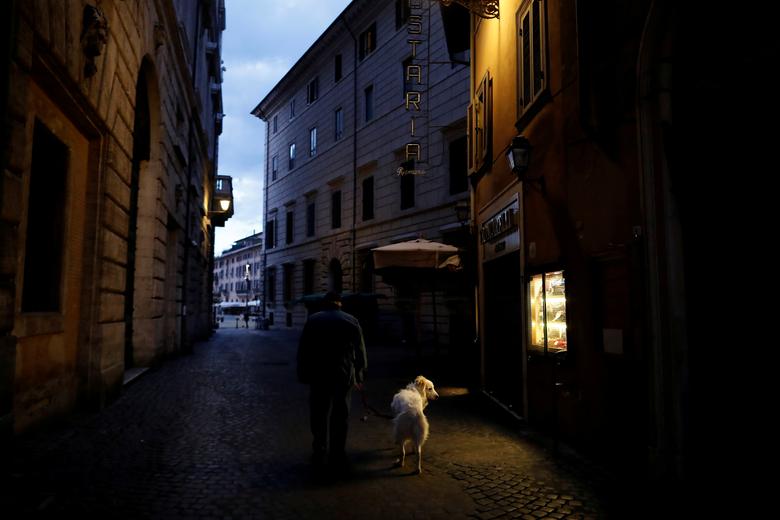 Một người đàn ông dắt chó đi dạo trên một con phố gần quảng trường Piazza Navona ở Rome, Ý, ngày 28/4.
