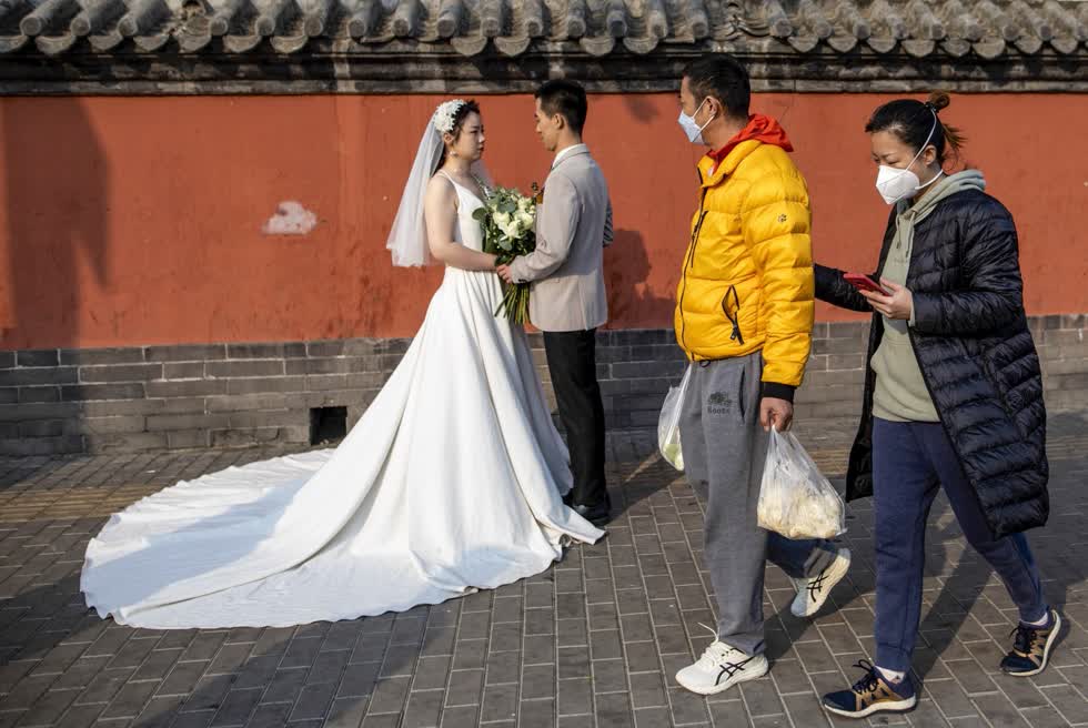 Người dân đeo khẩu trang bảo vệ mình đi qua một cặp đôi đang chụp ảnh cưới tại Bắc Kinh. Ảnh: EPA.