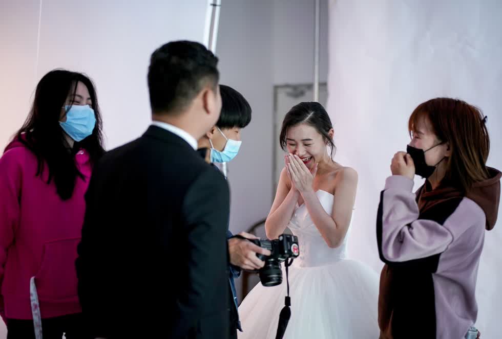 Cô dâu Luo Jian cười tươi khi xem lại ảnh cưới đã được chụp trước đó. Ảnh Reuters.