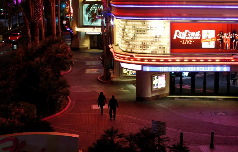   Một cặp vợ chồng đi bộ trên vỉa hè, ngang qua sòng bạc khách sạn Flamingo đang bị đóng cửa ở Las Vegas.  