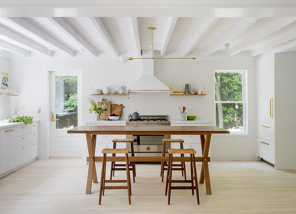 Nhà bếp với tông màu trắng kết hợp hài hòa với bàn ghế gỗ.