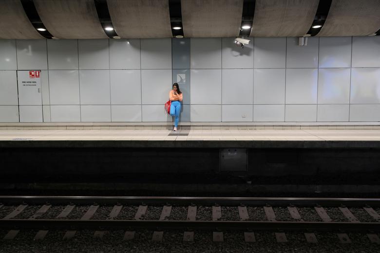   Một người đi làm đơn độc đứng trên sân ga của một nhà ga vắng vẻ trong giờ cao điểm buổi sáng ở Sydney, Australia.  