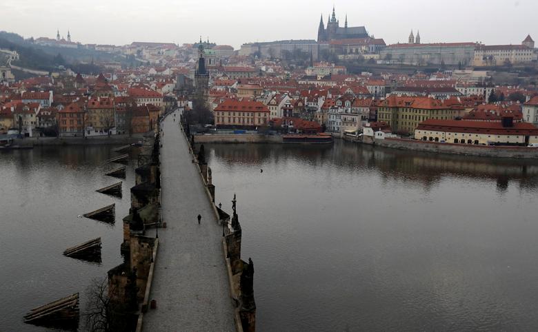   Một người đàn ông đi ngang qua cây cầu Charles trống vắn ở Prague, Cộng hòa Séc.  