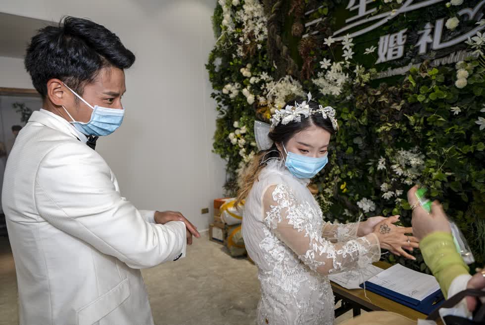 Luo Jian (trái) và Cheng Yishuang khử trùng tay tại studio chụp ảnh cưới ở Vũ Hán. Ảnh: Tân Hoa Xã.