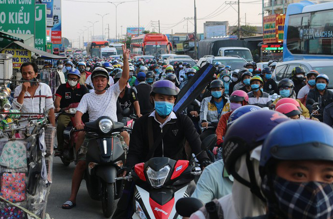 Ngay ngã tư đoạn giao giữa Quốc lộ 1A với đường Nguyễn Hữu Trí (tại huyện Bình Chánh), mật độ người và phương tiện ngày càng đông, chủ yếu là xe máy và xe khách giường nằm.