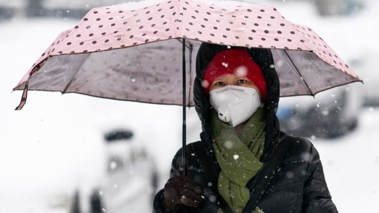 Một phụ nữ đeo khẩu trang phòng dịch ngừa lây nhiễm virus corona trong trận tuyết rơi tại Bắc Kinh, Trung Quốc.