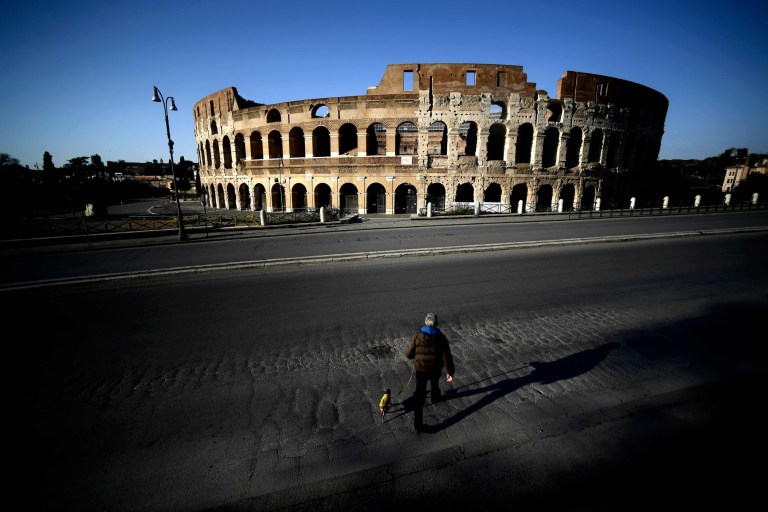   Một người đàn ông dắt chó đi dạo ở trung tâm Rome. Ảnh: AFP.  