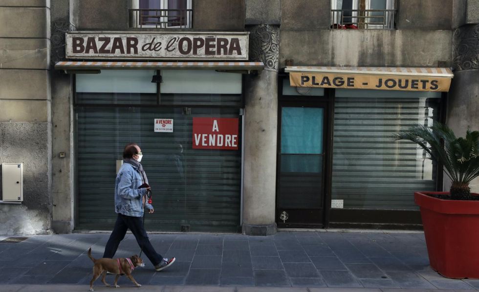   Người đàn ông dắt chú chó đi ngang qua một cửa hàng đã đóng cửa ở Nice, Pháp, ngày 17/11/2020. (Ảnh: Reuters).  