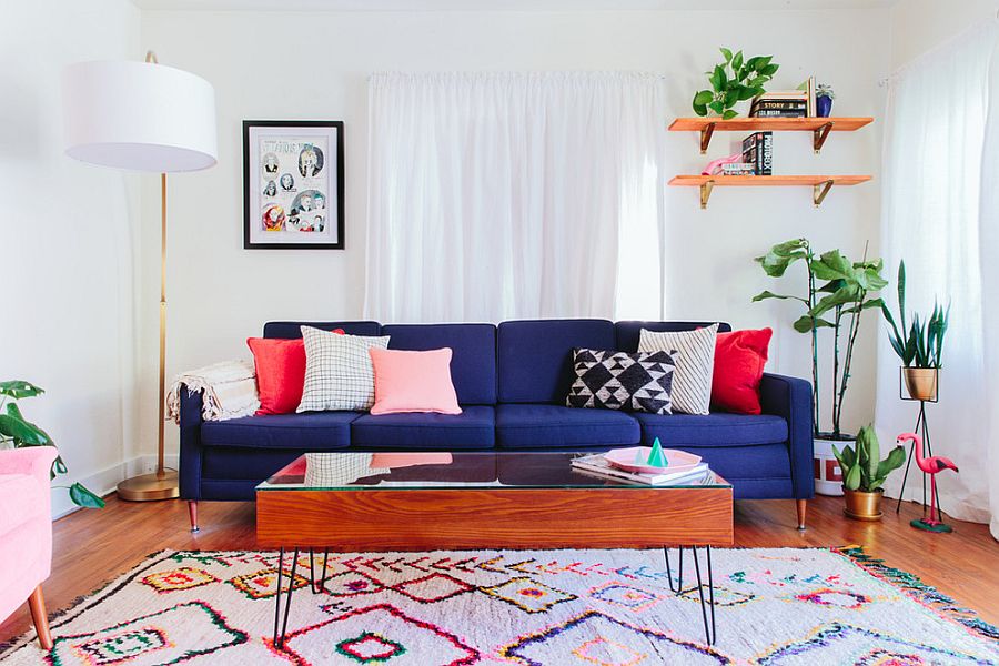 Sofa màu xanh kết hợp với thảm đầy màu sắc và gối tạo điểm nhấn mang đến màu sắc cho phòng khách chiết trung màu trắng này.