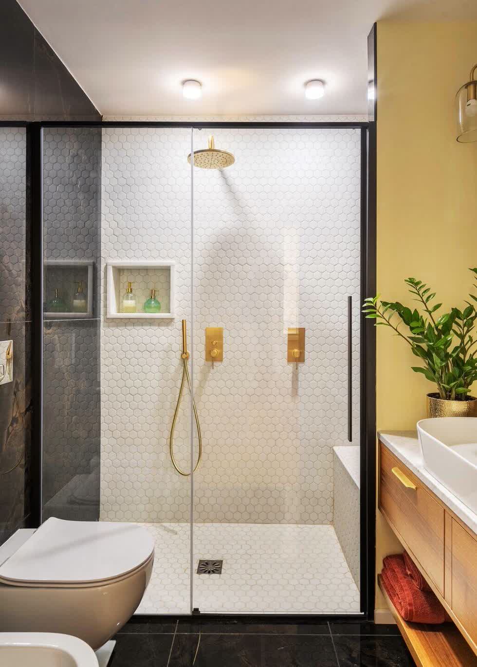 Kính cường lực khung nhôm đen được sử dụng làm vách ngăn giữa hai không gian tắm và vệ sinh.