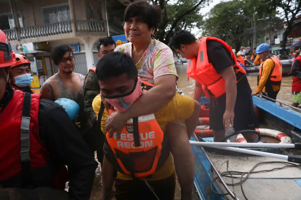 Nhân viên cứu nạn cõng người dân ra khỏi thuyền để di chuyển đến nơi an toàn. Ảnh: AP
