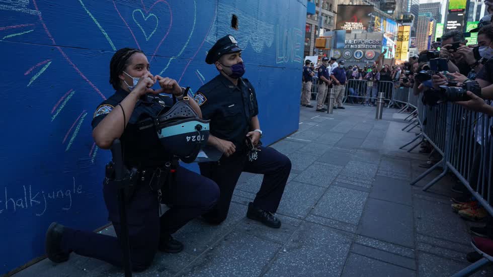 Hai cảnh sát New York quỳ gối trước đám đông người biểu tình ở Times Square hôm 31/5. Ảnh: AFP