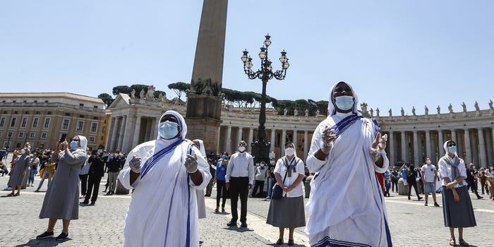 Các nữ tu đeo khẩu trang và găng tay cầu nguyện  tại Quảng trường Thánh Peter ở thành phố Vatican hôm Chủ nhật.