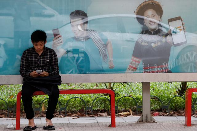 Một người dùng Internet trước bảng quảng cáo dịch vụ kết nối 4G tại một bến xe buýt ở Hà Nội, Việt Nam Ngày 29/8/2017. Ảnh: Reuters