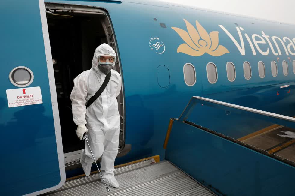 Một nhân viên y tế sau khi phun thuốc khử trùng bên trong máy bay của Vietnam Airlines tại sân bay Nội Bài. Ảnh: Reuters.