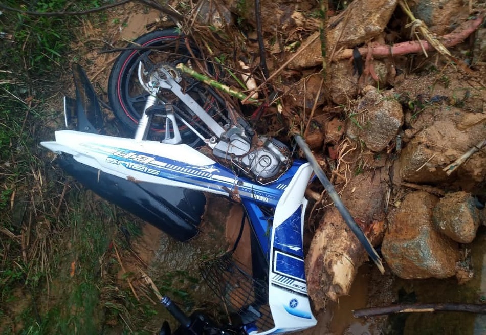 Chiếc xe máy của hai thanh niên bị đất đá vùi trên đường Trường Sơn Đông. Ảnh: Vnexpress