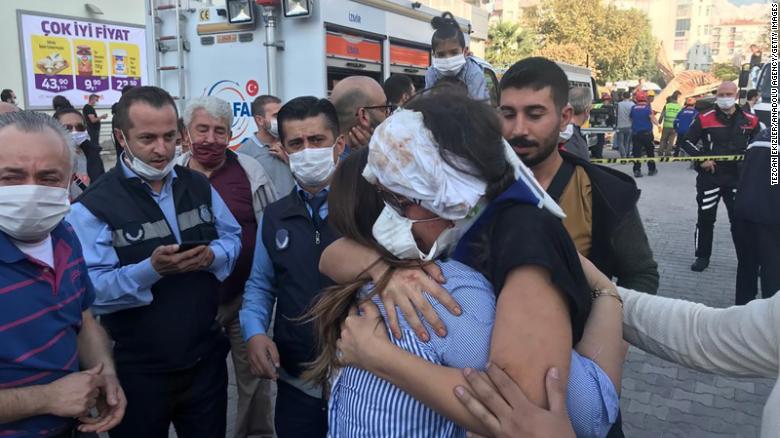   Một phụ nữ bị thương ôm người thân của mình sau khi được cứu khỏi mảnh vỡ của một tòa nhà ở quận Bornova, tỉnh Izmir. Ảnh: CNN.  