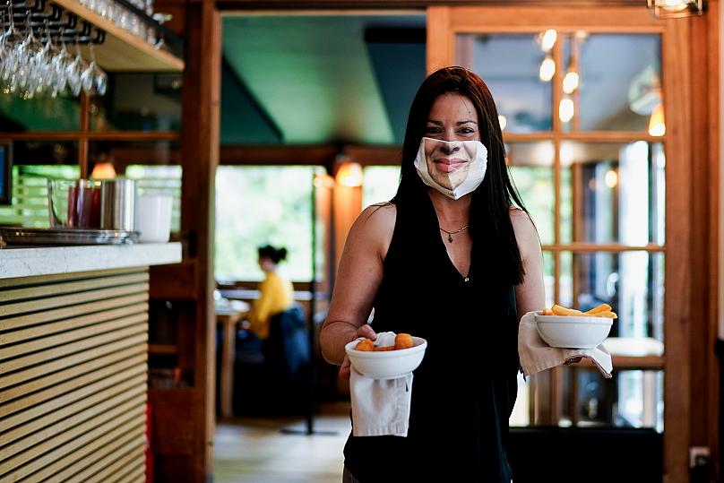 Người phục vụ đeo khẩu trang bảo vệ với hình ảnh khuôn mặt của cô ấy, trong nhà hàng Lodge. Brussels, Bỉ. Ảnh: AFP.