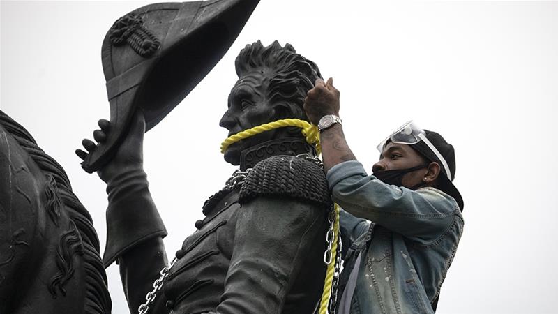 Người  biểu tình  đang buộc dây để kéo đổ bức tượng.