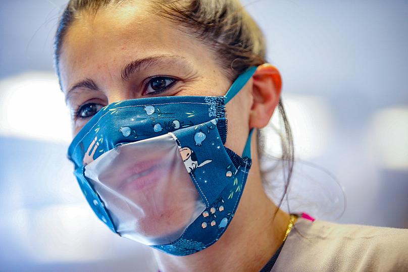 Một người phụ nữ đeo khẩu trang với tấm che miệng trong suốt, bởi cô phục vụ cho những người không thể nghe được tại Brussels, Bỉ. Ảnh: AFP.