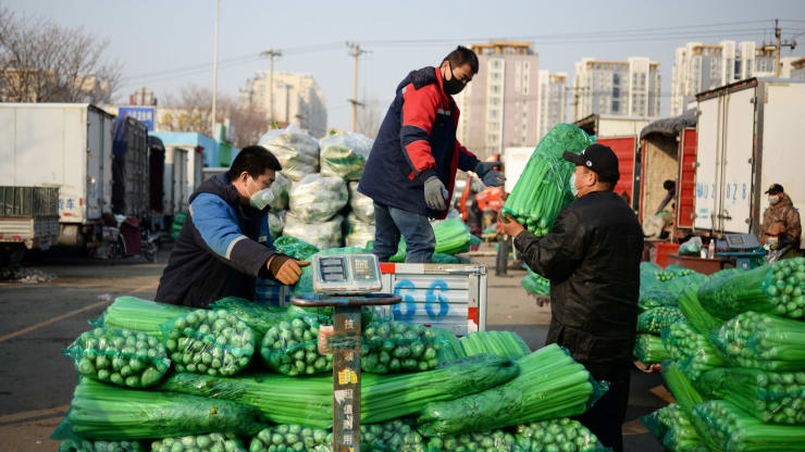 Những người đeo khẩu trang di chuyển các gói rau tại một chợ bán buôn các sản phẩm nông nghiệp tại Bắc Kinh, Trung Quốc. Ảnh: Reuters