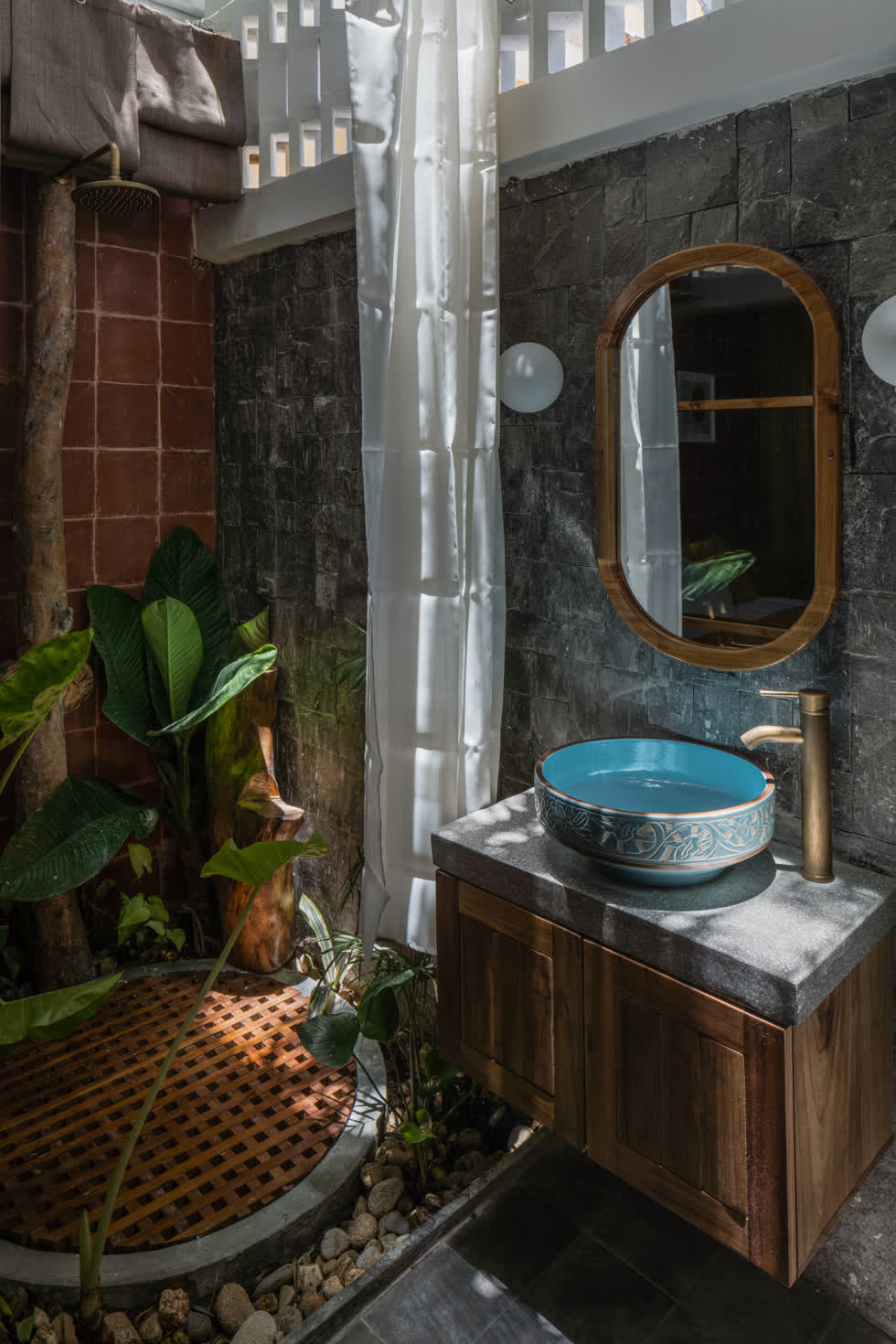 Phòng tắm được bày trí độc đáo với sỏi và cây xanh, ngăn cách với phòng ngủ bởi một lớp cửa mở trượt, khi cần có thể kéo rèm để tạo sự riêng tư.