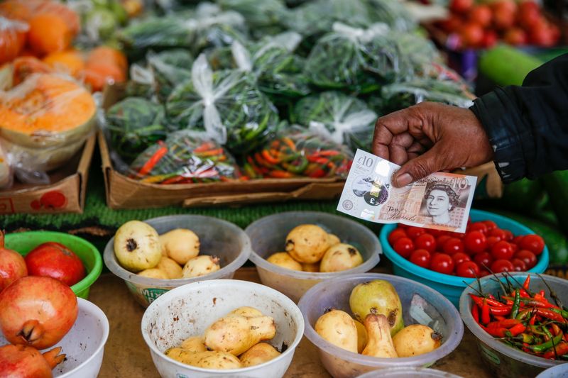 Khách hàng cầm dùng tiền giấy để mua trái cây và rau quả tại một khu chợ ở Poplar, London, Vương quốc Anh. Ảnh: Bloomberg