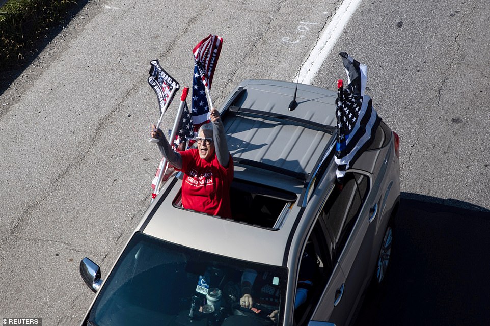   Một người ủng hộ giơ cao cờ Mỹ ủng hộ Tổng thống Mỹ. Ảnh: Reuters.  