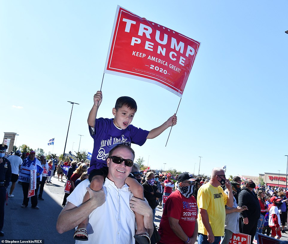 Một đứa trẻ cầm biểu ngữ Trump-Pence 2020 khi ngồi trên vai cha mình ở Đảo Staten. Ảnh: Daily Mail.