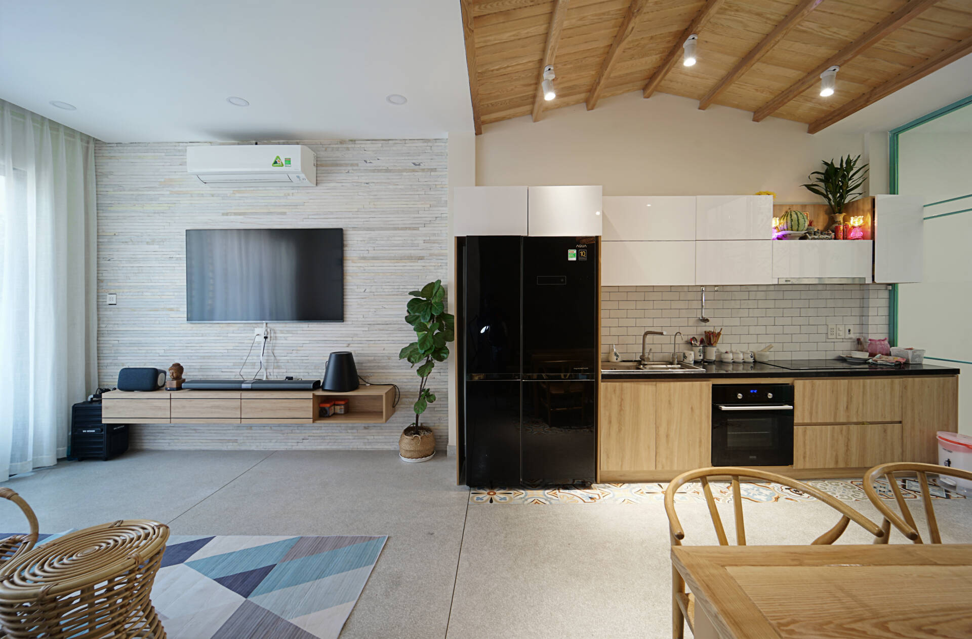 Phòng khách và bếp được thiết kế liền mạch nhưng vẫn có sự phân chia không gian bằng việc thay đổi hệ trần. 