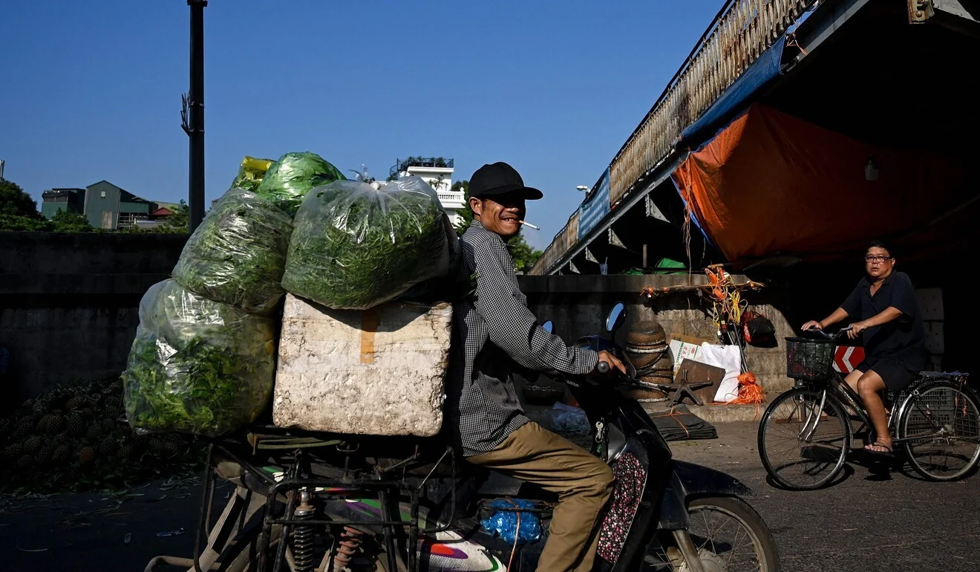   Một người bán hàng vận chuyển rau tại chợ đầu mối ở Hà Nội. Ảnh: AFP  