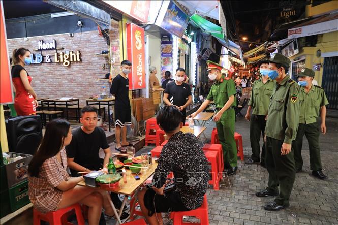 Lực lượng chức năng nhắc nhở các chủ hộ kinh doanh thực hiện nghiêm chỉ định phòng chống dịch COVID-19 tại phố Tạ Hiện, phường Hàng Buồm. Ảnh: TTXVN