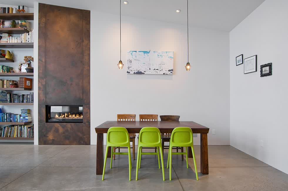 Bộ ba ghế màu xanh lá cây mang lại màu sắc cho phòng ăn tối giản tinh tế.
