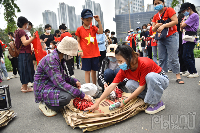 Triệu Thị Thủy Tiên - leader nhóm Xanh Việt Nam - Đầu cầu Hà Nội đeo khẩu trang mặc áo đỏ đang phân chia dụng cụ cho các thành viên trong nhóm.