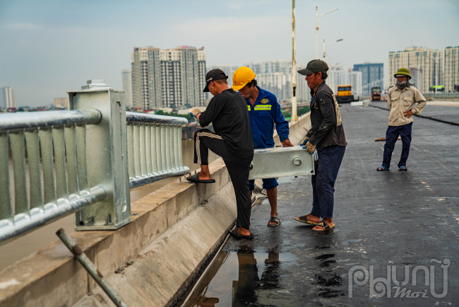 Công nhân tiến hành lắp đặt các đoạn lan can còn lại của cây cầu Vĩnh Tuy