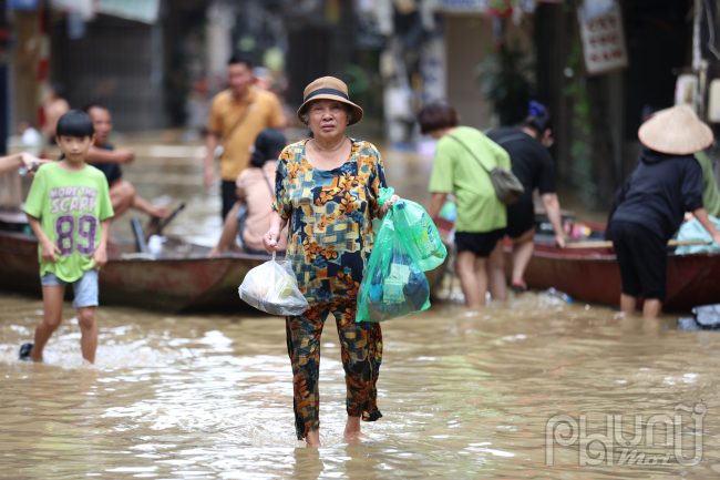 Bà Hoài người dân nơi này cho hay. Nước ngập mấy ngày nay tôi già yếu có tuổi không dám lội nước mò mầm đi lại. Thật may quá sáng nay có dịch vụ chèo thuyền đưa đón tận nhà lại an toàn nên tôi mới dám ra ngoài mua đồ thiết yếu.