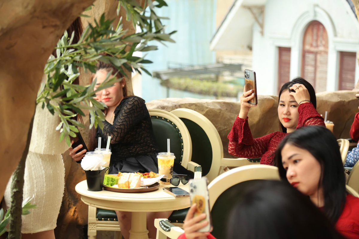 Từ tầng trệt đến tầng thượng, quán cà phê chật kín khách, tiếng nói cười rộn rã vang vọng khắp không gian.