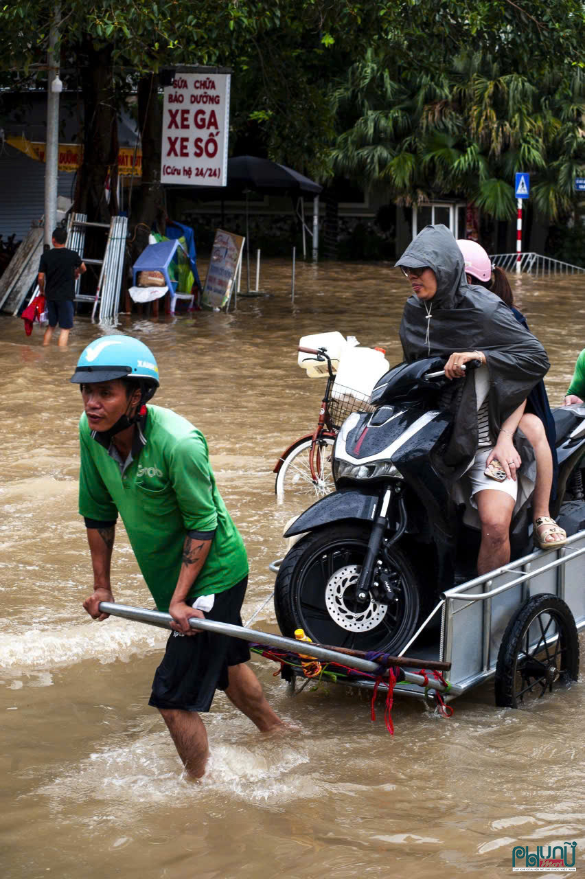 Trước tình trạng nhiều tuyến phố vẫn chìm trong nước sau mưa lớn, người dân buộc phải tìm đủ cách để di chuyển. Không ít người đã tận dụng xe cải tiến, kéo cả xe máy và người qua những đoạn đường ngập sâu. Hình ảnh này xuất hiện trên nhiều tuyến phố Hà Nội sáng 1/10, phản ánh rõ sự ứng biến của người dân trong bối cảnh giao thông gặp nhiều trở ngại.