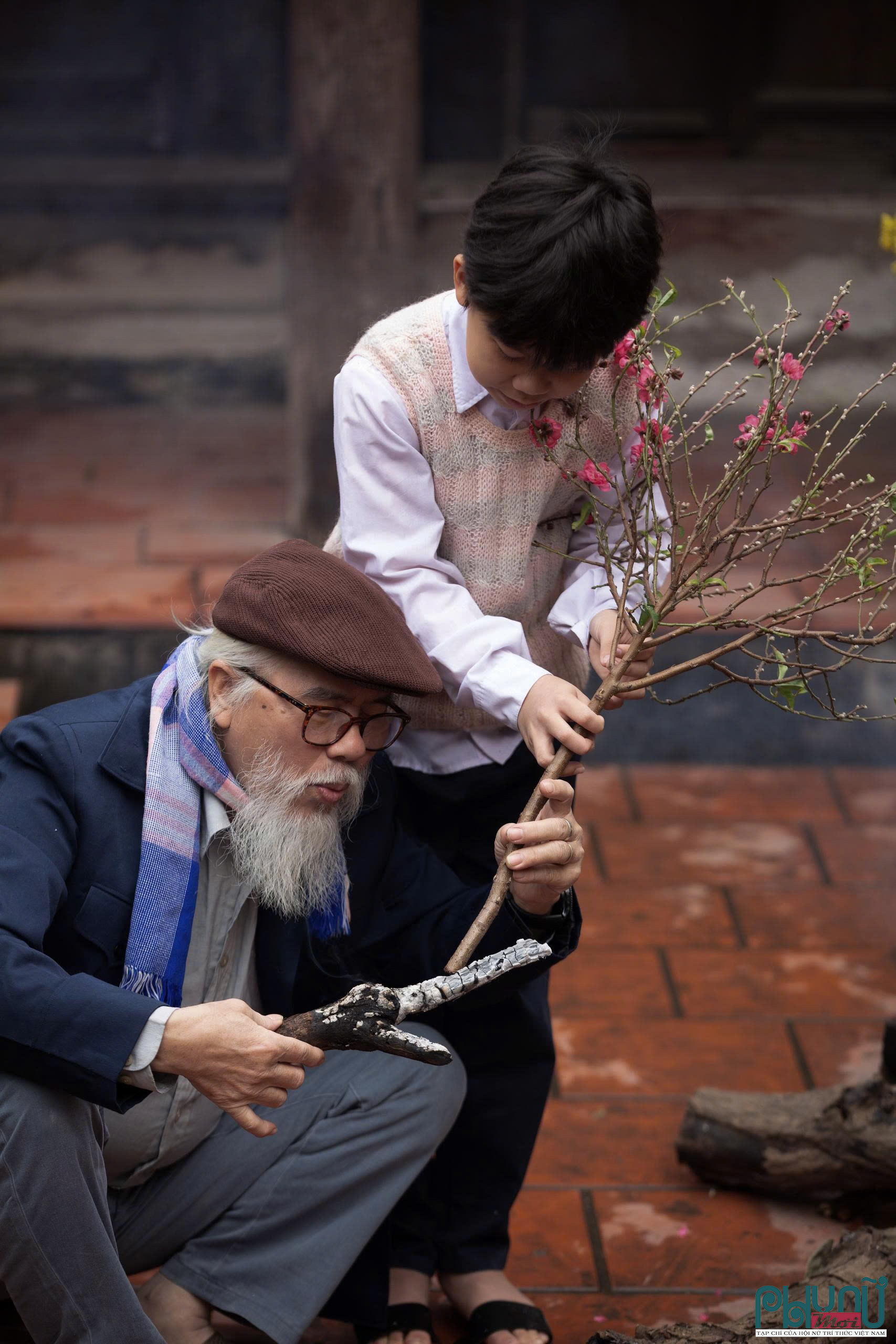 Trong khi chờ bánh chín, có những khoảnh khắc rất riêng. Hai ông cháu ngồi bên hiên nhà, đốt gốc đào cho than hồng rực, rồi cẩn thận cắm lại cành đào vừa mang từ chợ về. Ông bảo phải hơ gốc như thế thì hoa mới bền, nở đúng dịp. Đứa cháu chăm chú lắng nghe, tay lấm lem tro nhưng ánh mắt đầy háo hức. Những việc tưởng nhỏ ấy lại trở thành ký ức không dễ phai mờ.