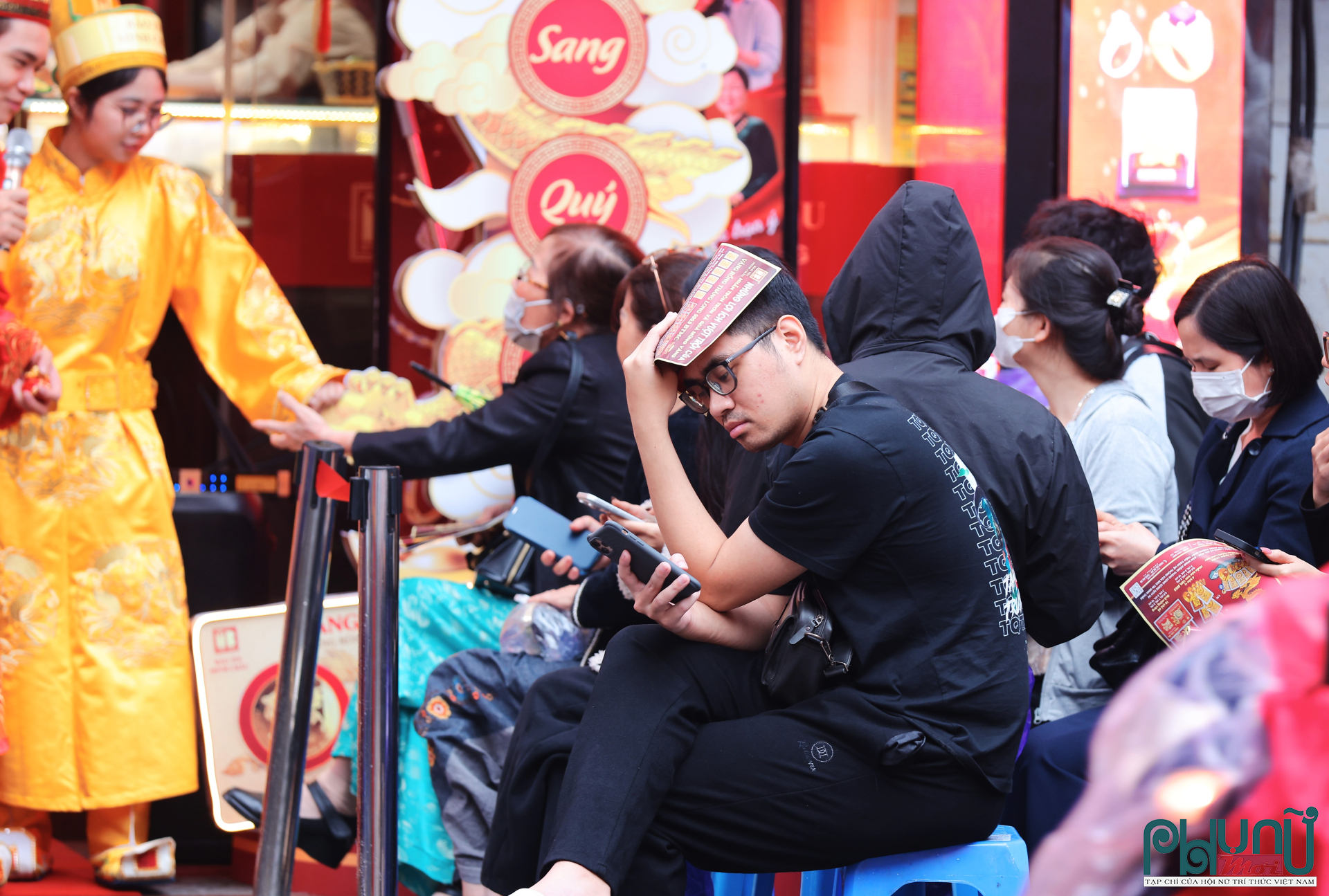 Khách hàng check giá vàng trong khi ngồi chờ đến lượt mua vàng