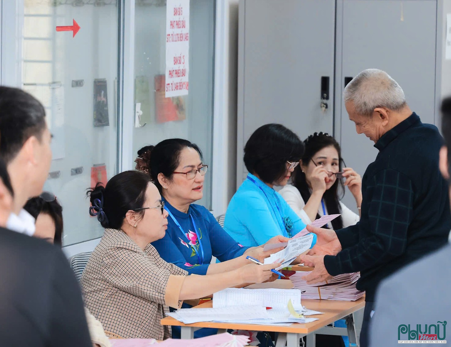 Người dân xếp hàng nhận phiếu bầu cử theo hướng dẫn của các thành viên tổ bầu cử