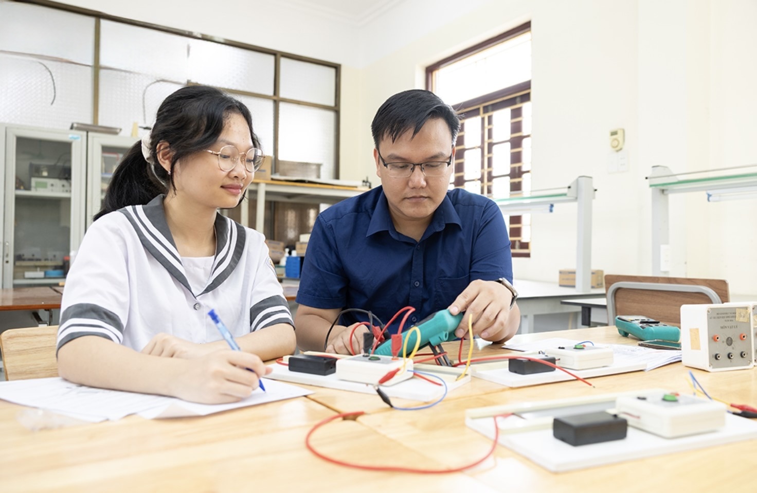Thầy giáo Nguyễn Hải Dương hướng dẫn Nguyễn Thị Bích Ngọc kỹ năng thực hành Vật lý. Ảnh: BNB