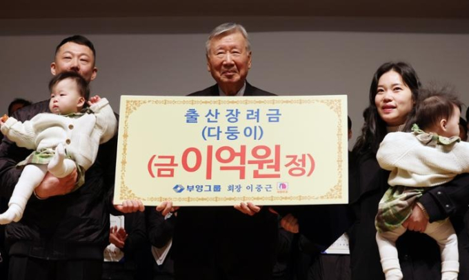 Chủ tịch Tập đoàn Booyoung Lee Jong-keun (giữa) chụp ảnh cùng gia đình một nhân viên sau khi trao cho họ 200 triệu won (gần 4 tỷ VNĐ) tiền mặt trong buổi lễ đón năm mới tại trụ sở công ty ở Seoul hôm 5/2.