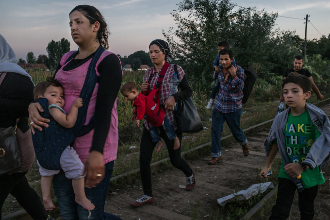 Ngày 30 tháng 8 năm 2015. Roujin Sheikho, bên trái, từ Syria, bế con gái Widad là con trai Nabih, bên phải, đi bộ cùng cô và những người tị nạn Syria khác xuống đường sắt trước khi đi qua Hungary từ Horgos, Serbia.  (Ảnh của Mauricio Lima)
