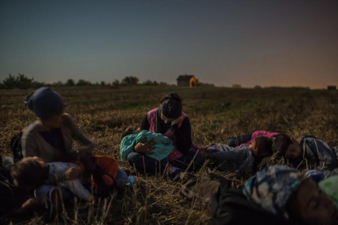 Ngày 31 tháng 8 năm 2015. Các thành viên của gia đình Majid từ Syria đang ôm đứa con nhỏ trong vòng tay trên cánh đồng lúa mì, họ đang chờ đợi để vượt qua hàng rào dây thép gai ở Horgos vào Hungary.  (Ảnh của Mauricio Lima)