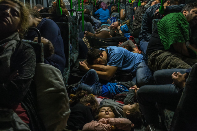 Ngày 5 tháng 9 năm 2015, Ahmad Majid, mặc áo phông màu xanh, ngủ trên sàn xe buýt với các con, anh trai Farid Majid, mặc áo len màu xanh lá cây bên phải, và các thành viên khác trong gia đình họ và hàng chục người tị nạn khác, họ đang rời Budapest (Hungary) trên đường đến Vienna (Áo). Hàng trăm ngàn người tị nạn, chủ yếu đến từ Afghanistan, Iraq và Syria, đã rời bỏ nhà cửa, mạo hiểm mạng sống của họ trong những chuyến đi thuyền nguy hiểm, vượt biên bất hợp pháp và tiếp tục hành trình dài trên xe buýt và xe lửa để xin tị nạn ở Tây Âu và vùng Scandinavia.  (Ảnh của Mauricio Lima)