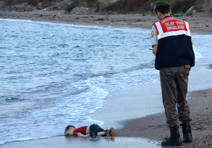 Các sĩ quan ở Bodrum, Thổ Nhĩ Kỳ, trước thi thể của Alan Kurdi, một người tị nạn Syria đã dạt vào bờ vào tháng 9 năm 2015. Cậu bé 2 tuổi là một trong 12 người tị nạn bị chết đuối ngày hôm đó trong một nỗ lực thất bại để chèo thuyền đến Đảo Kos của Hy Lạp. Bức ảnh này đã lan truyền khắp thế giới, thường có hashtag Thổ Nhĩ Kỳ có nghĩa là 