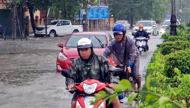 Nhiều phương tiện giao thông rất khó khăn khi lưu thông qua các tuyến đường ngập nước tại thành phố Đồng Hới. (Ảnh: Tá Chuyên/TTXVN)